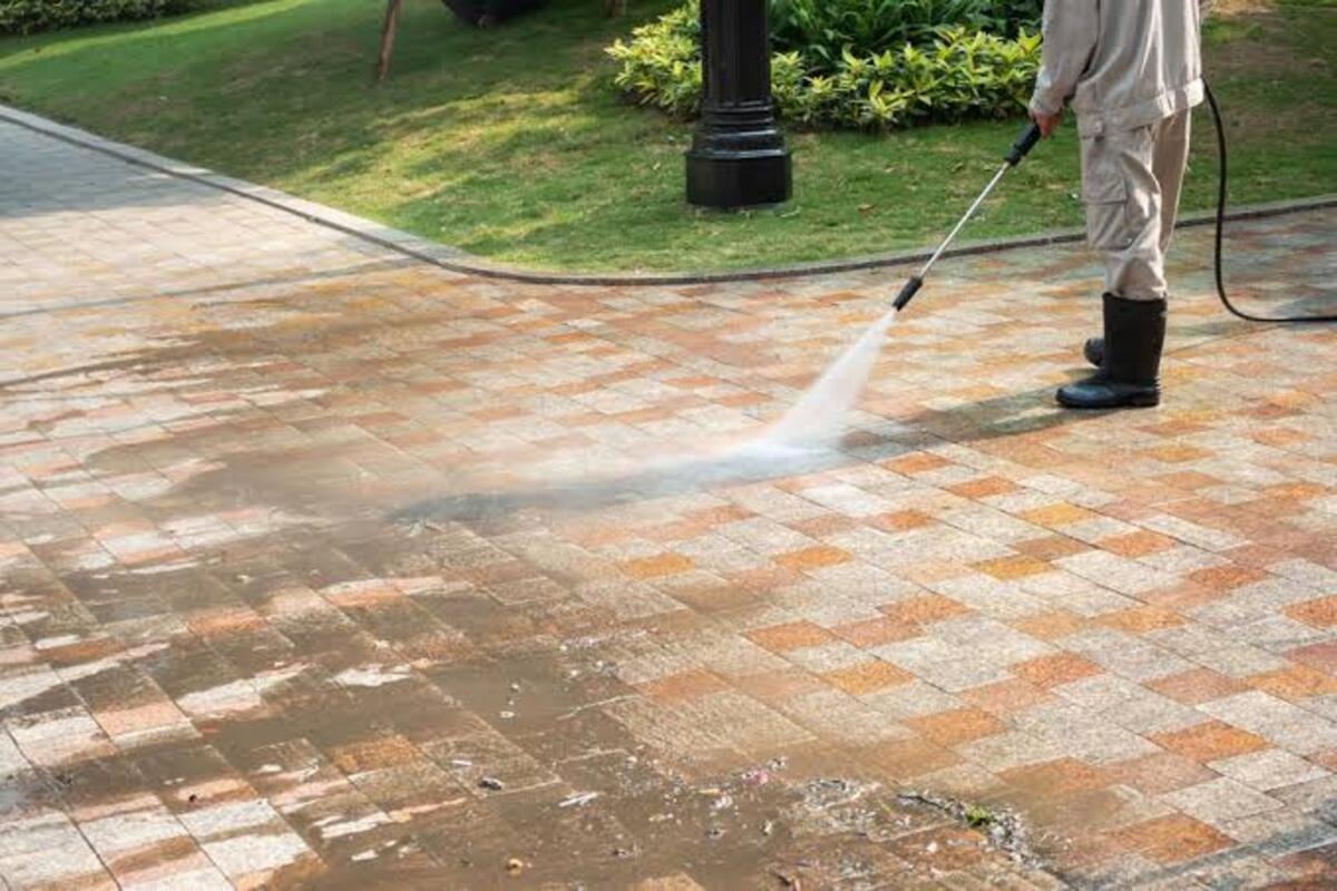 Professional pressure washing a concrete driveway with a commercial surface cleaner in Erie, PA.
